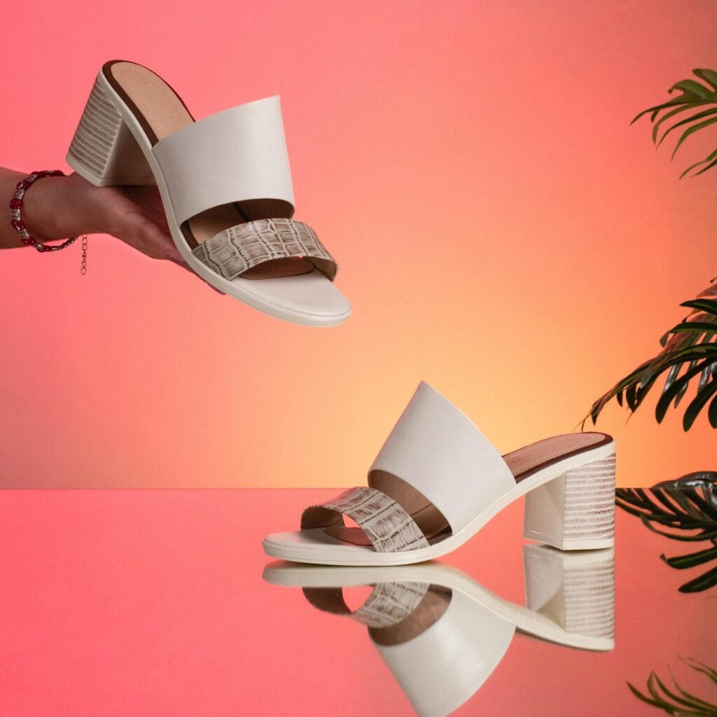 Elegant white heeled sandals displayed against a gradient background, highlighting fashion and style.