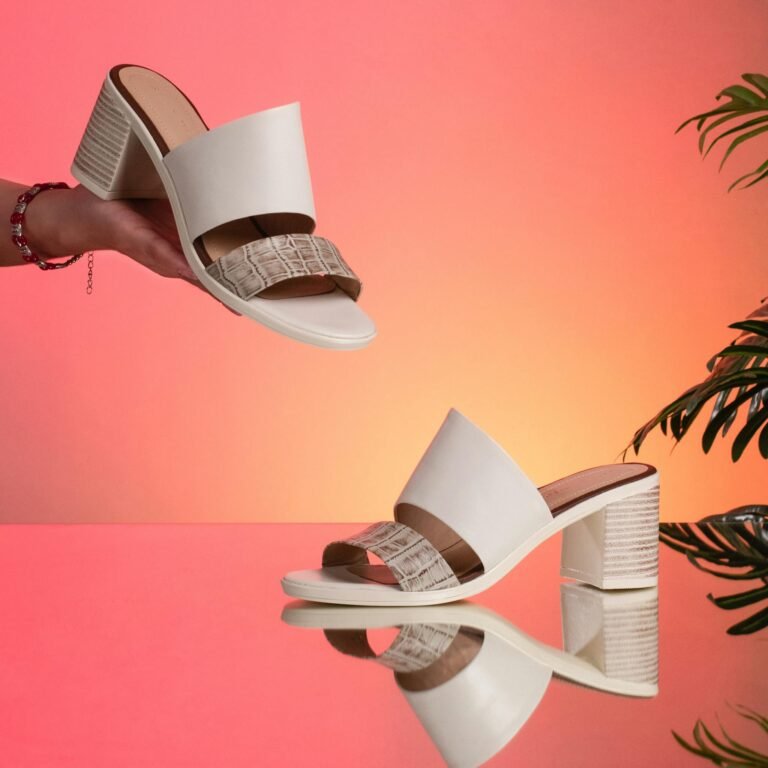 Elegant white heeled sandals displayed against a gradient background, highlighting fashion and style.